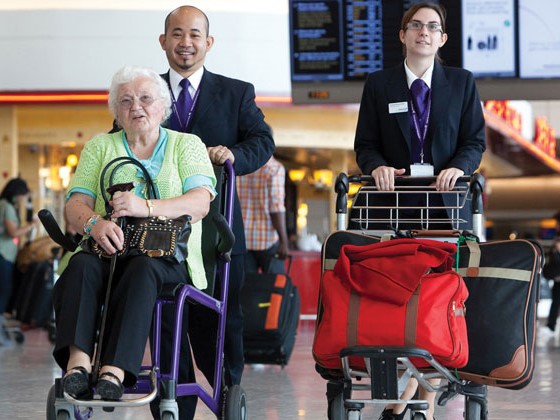 Personal de aeropuerto llevando a abuela en silla de ruedas